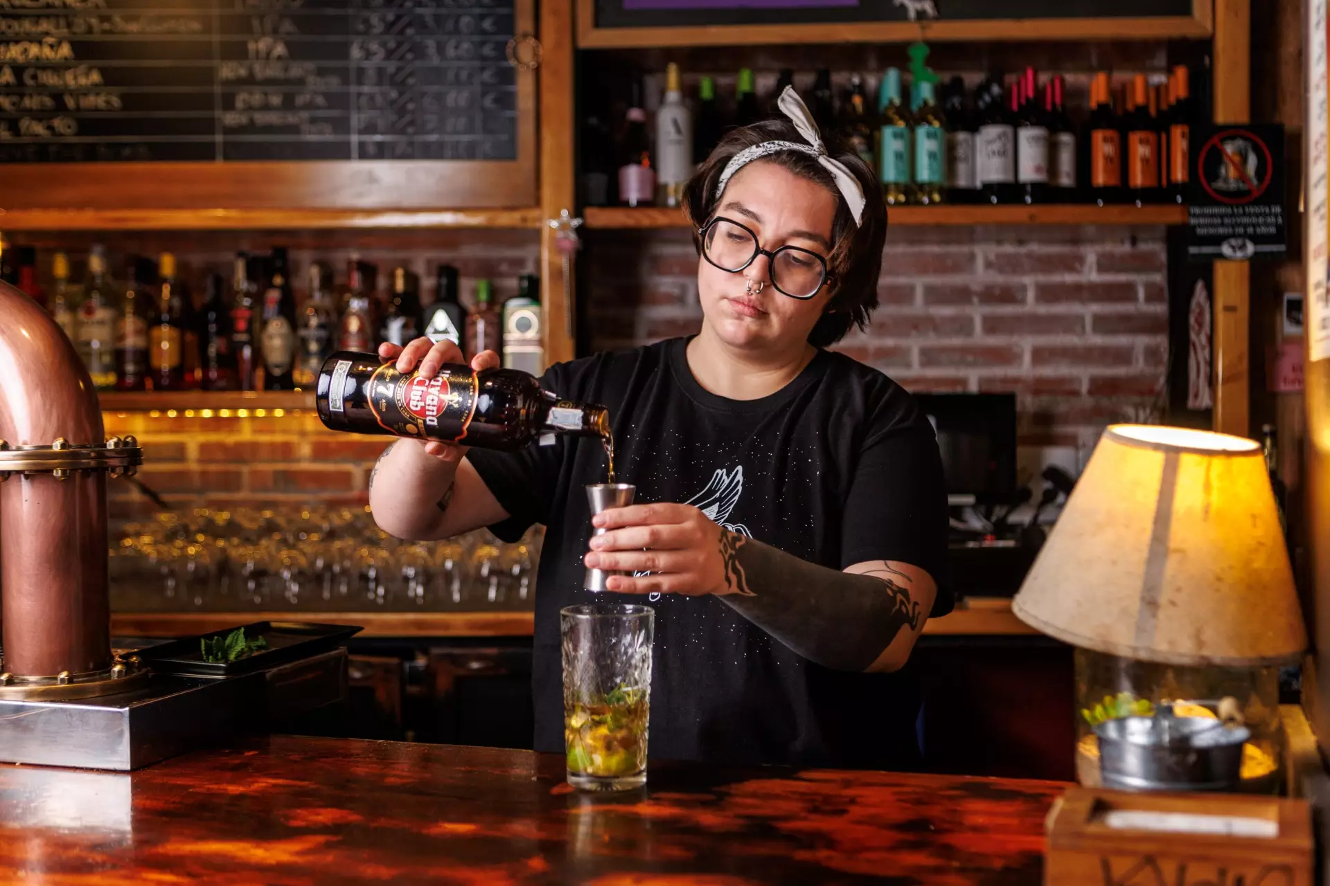 Mujer tras la barra preparando un cocktail