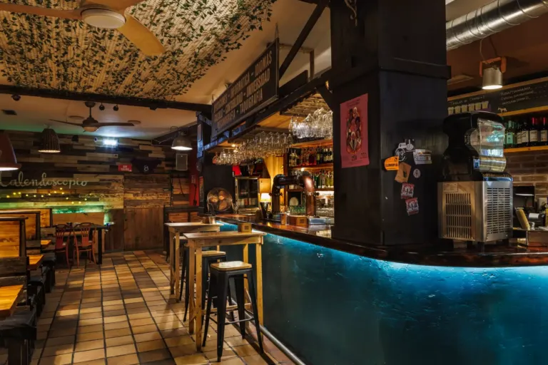 Barra del local con mesas y taburetes