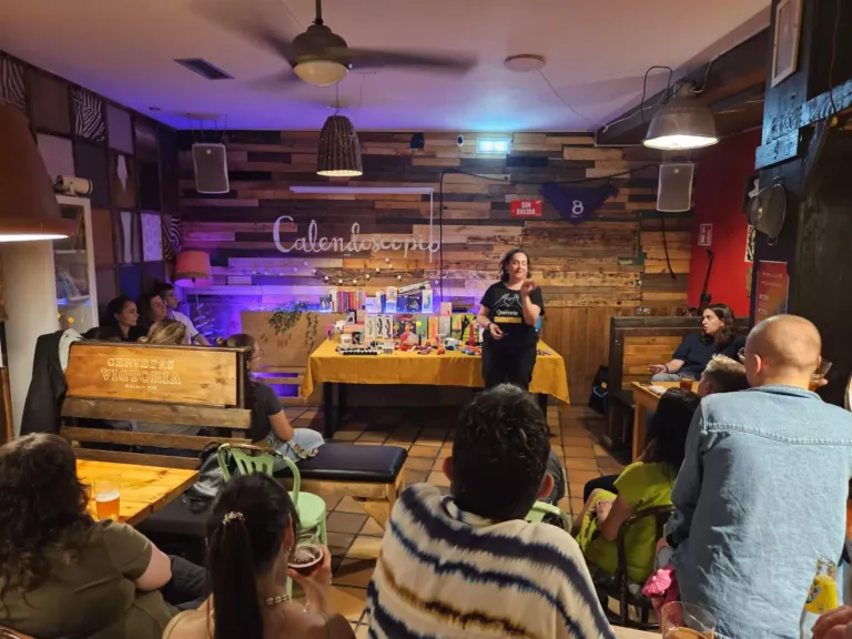Mujer hablando al público delante de una mesa con libros