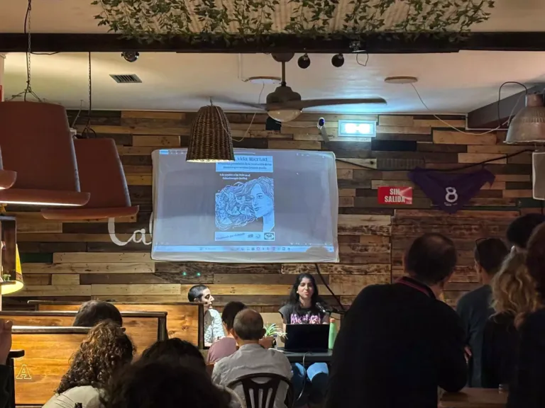 Mujer hablando mientras se proyecta una imagen de una portada de un libro